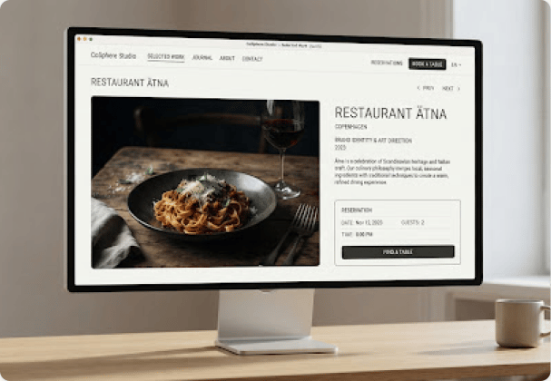 Desktop monitor showing a restaurant website with a pasta dish, wine, and a direct table reservation panel